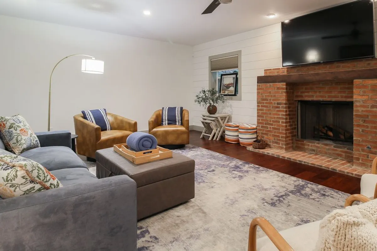 A spacious living room with a cozy fireplace, sofas, armchairs, and a coffee table. The scene evokes relaxation after a day of outdoor exploration, with ample space for both people and pets to unwind together.