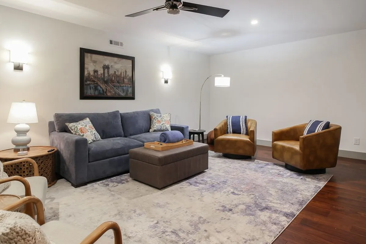 A cozy living room featuring a plush sofa, accent chairs, a coffee table, and stylish wall art. The seating area is arranged for comfort and conversation, with warm lighting and inviting decor that create a welcoming atmosphere ideal for relaxing or gathering with others.