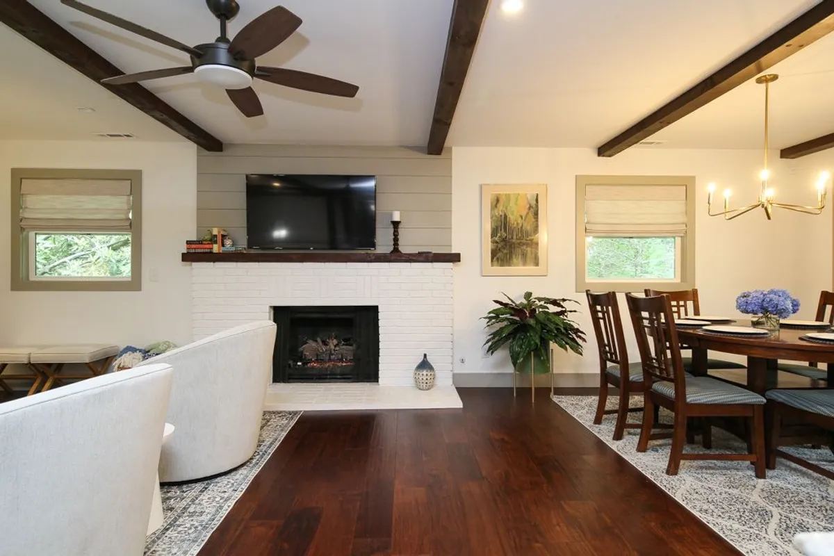 A cozy living space featuring a modern gas log fireplace, a comfortable sofa, a dining table, and a television. The room is styled for both relaxation and entertaining, with the warmth of the fireplace as a focal point.