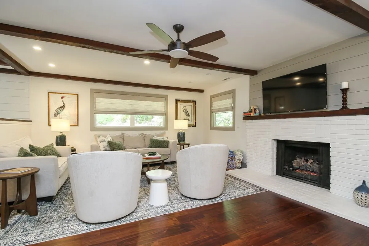 A cozy living room scene featuring a fireplace, plush sofas and armchairs, stylish artwork, and natural light. The arrangement invites socializing, board games, or relaxed evenings by the fire, aligning with the text's emphasis on both shared and private moments.